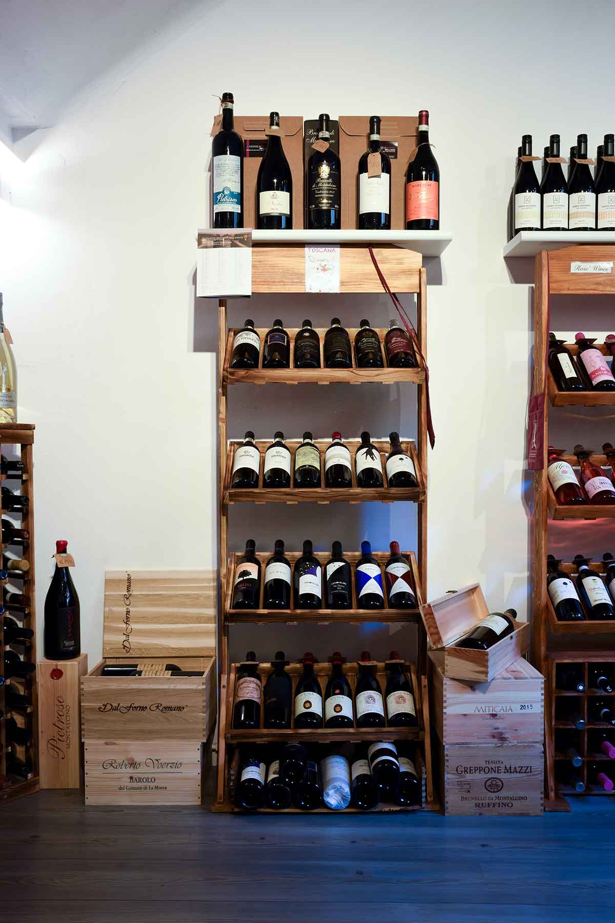 Scaffale dei vini rossi toscani con casse di legno nell'enoteca di Bellagio