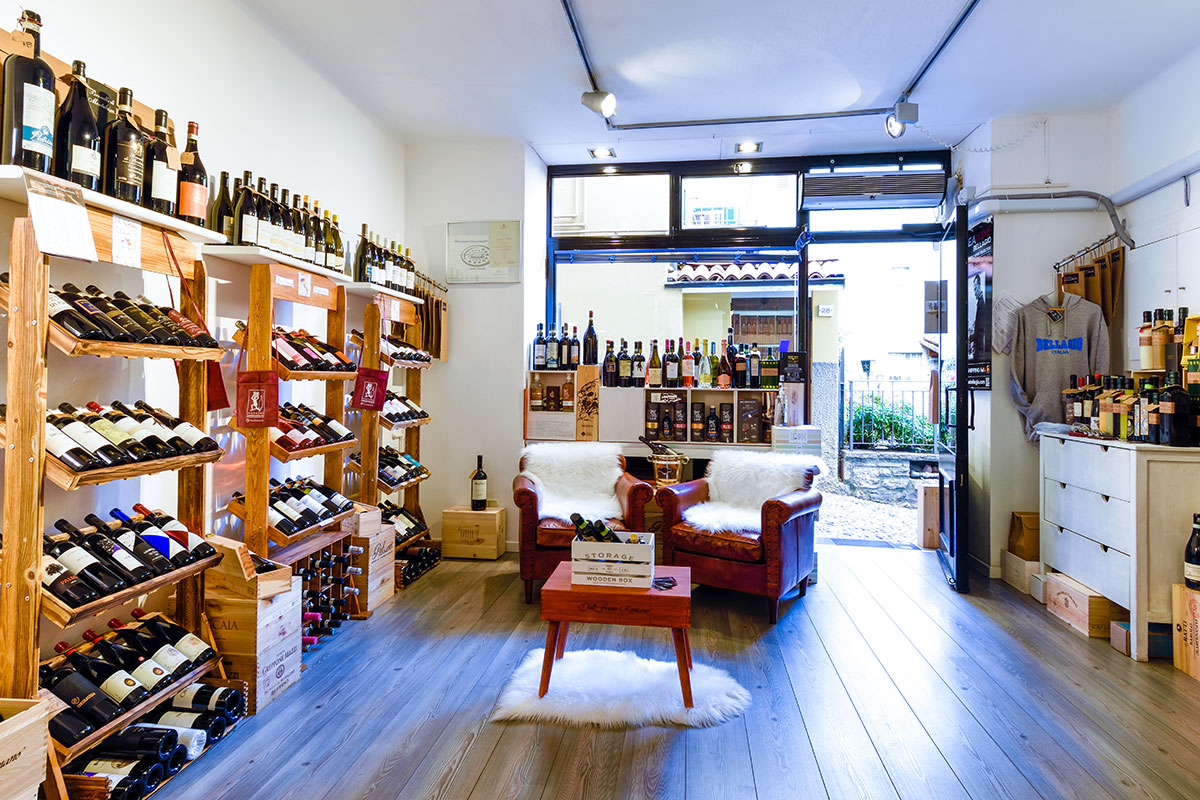 Interno dell'enoteca di Bellagio con scaffali di vini e poltrone