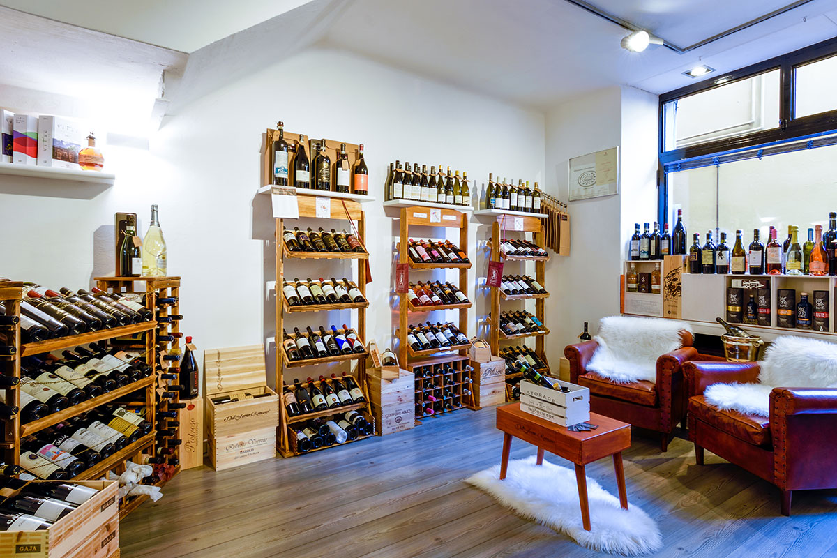 Angolo degustazione con poltrone in pelle tra gli scaffali dell'enoteca