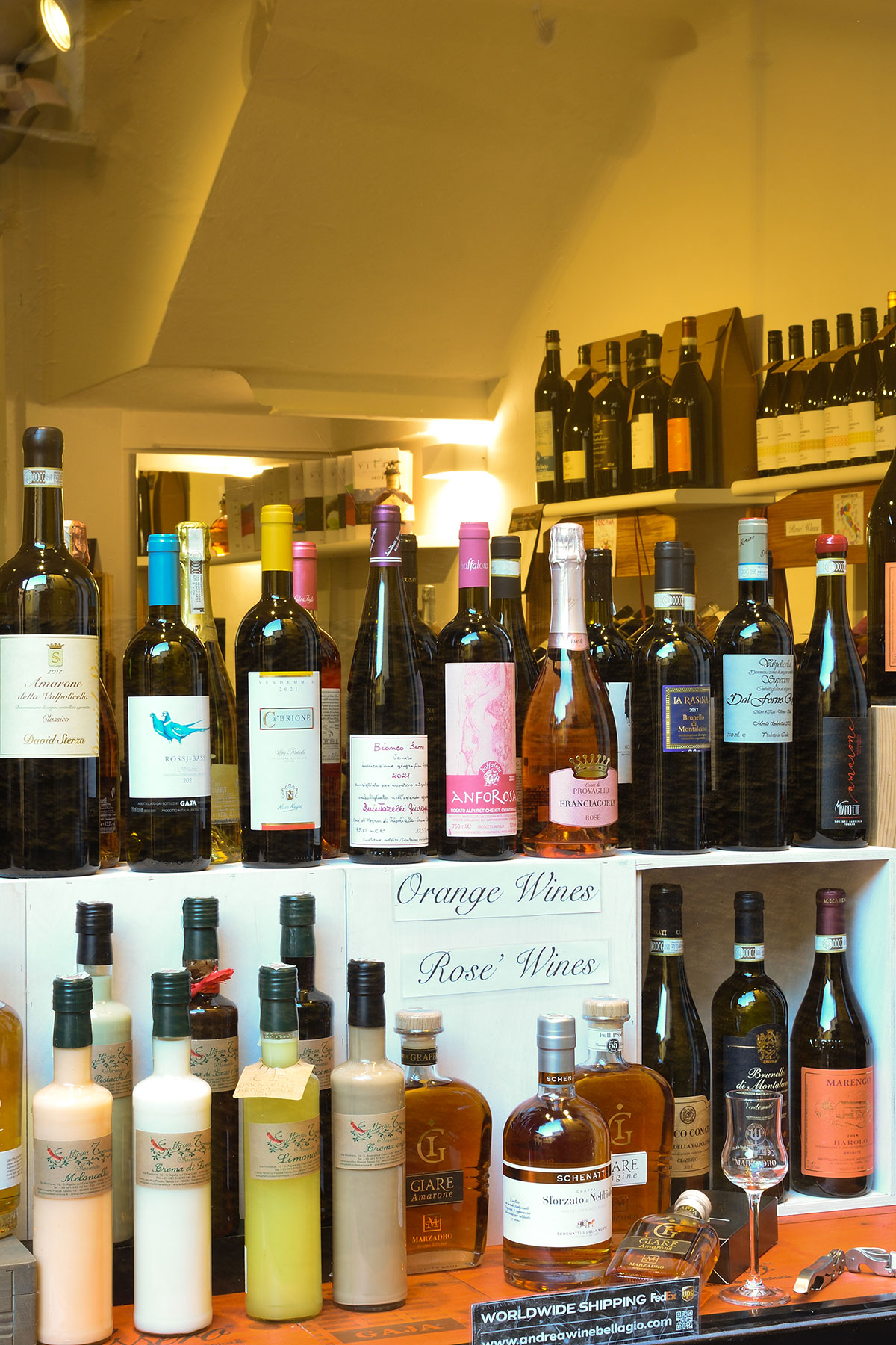 Scaffale di vini bianchi, rosati e macerati nell'enoteca di Bellagio